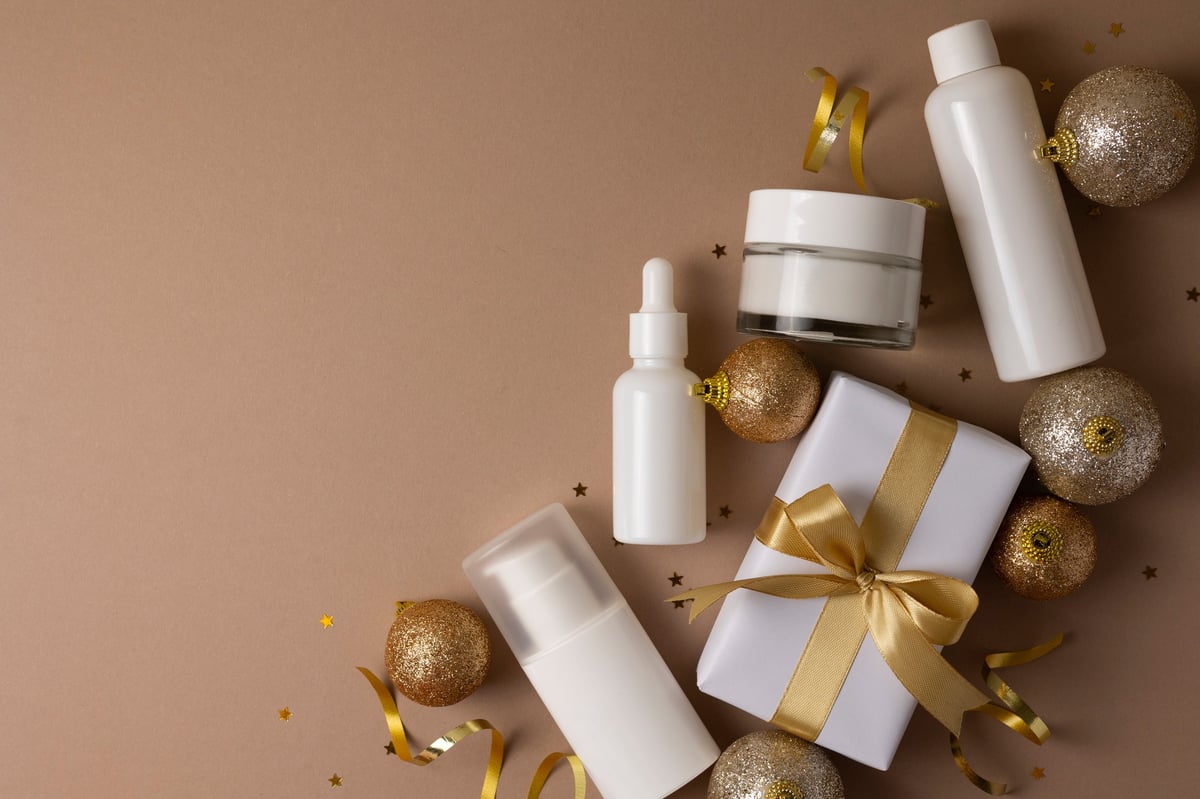 Luxury skincare gift set with festive Christmas decor and gift box on color background, holiday beauty concept.