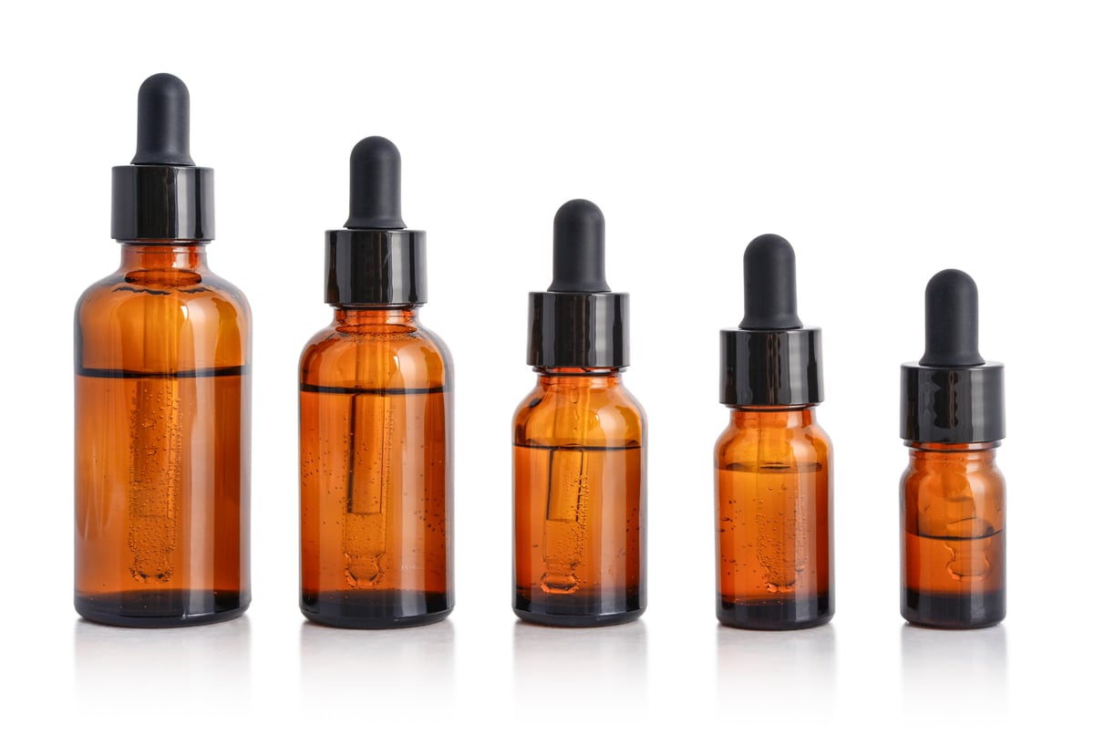 Five amber glass dropper bottles of different sizes isolated on white background with clipping path. Blank cosmetic packaging set for skincare, essential oils, serums, pharmaceuticals and branding mockups.